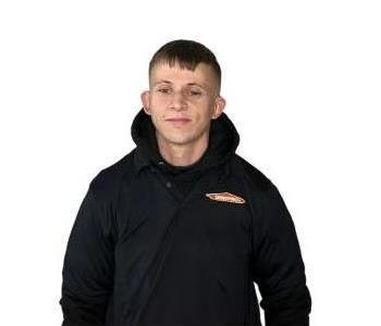 Male employee standing in front of background of wooden wall