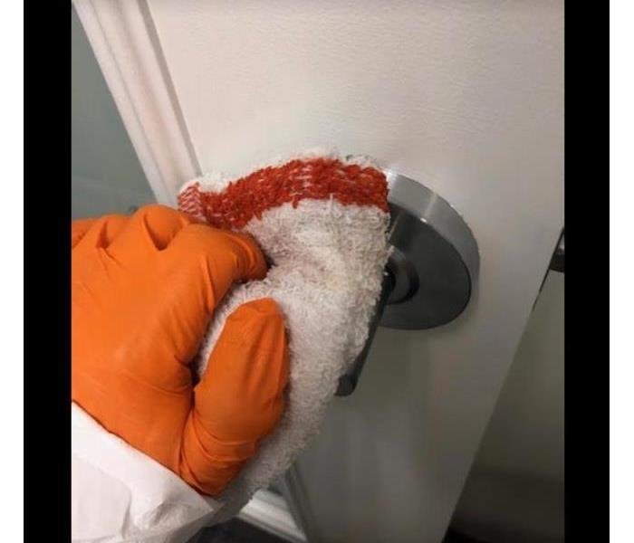 technician wearing orange glove wiping down door handle 
